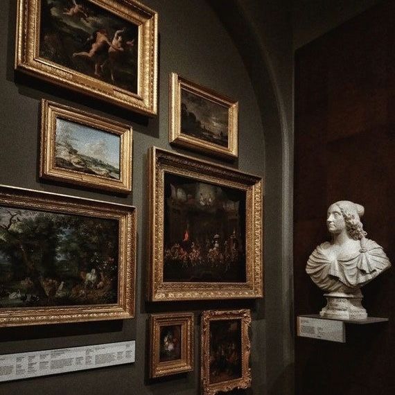 A dim museum wall with framed paintings
